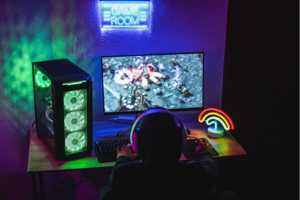 a game room with streaming gear including a gaming pc and neon lights