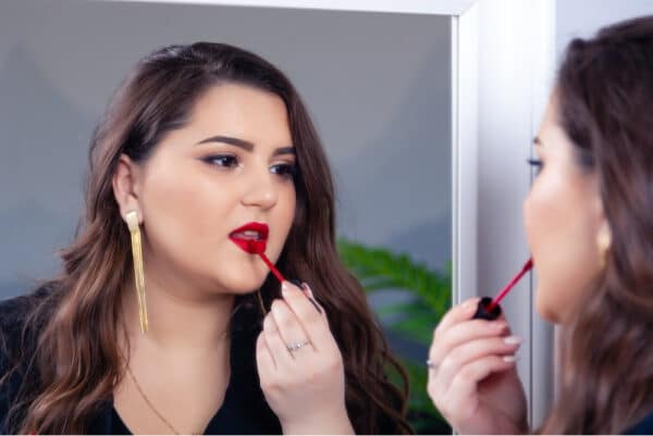 beauty blogger looking in the mirror putting on lip gloss