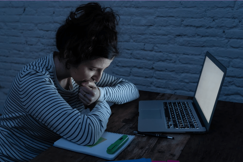 a woman feeling tired looking at a laptop screen trying to write a blog post