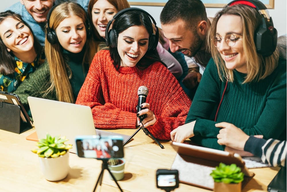 a group of friends with a laptop and a microphone recording a podcast